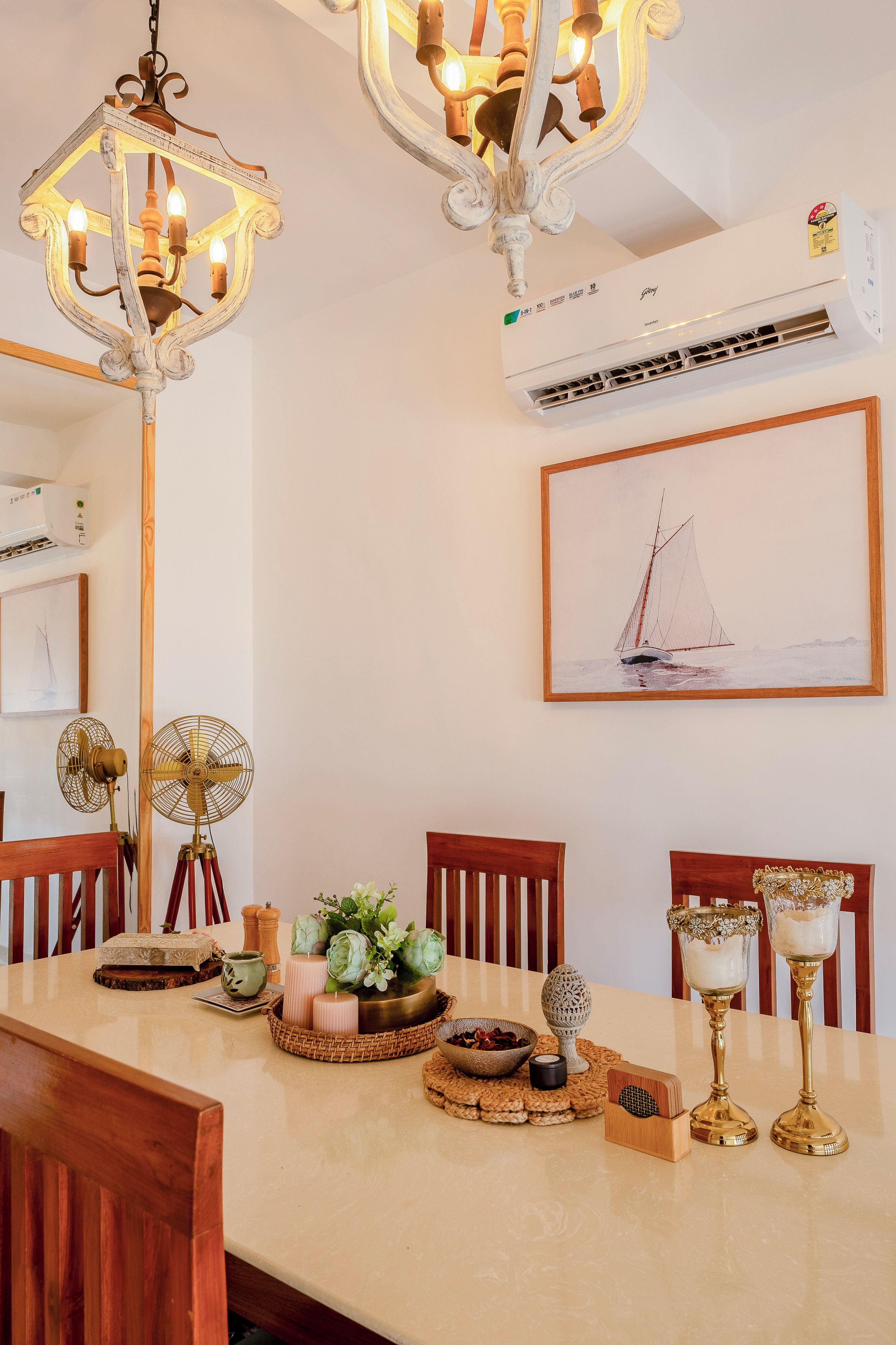 A dining area with a long table, chairs, a chandelier, an air conditioner, and a framed painting.