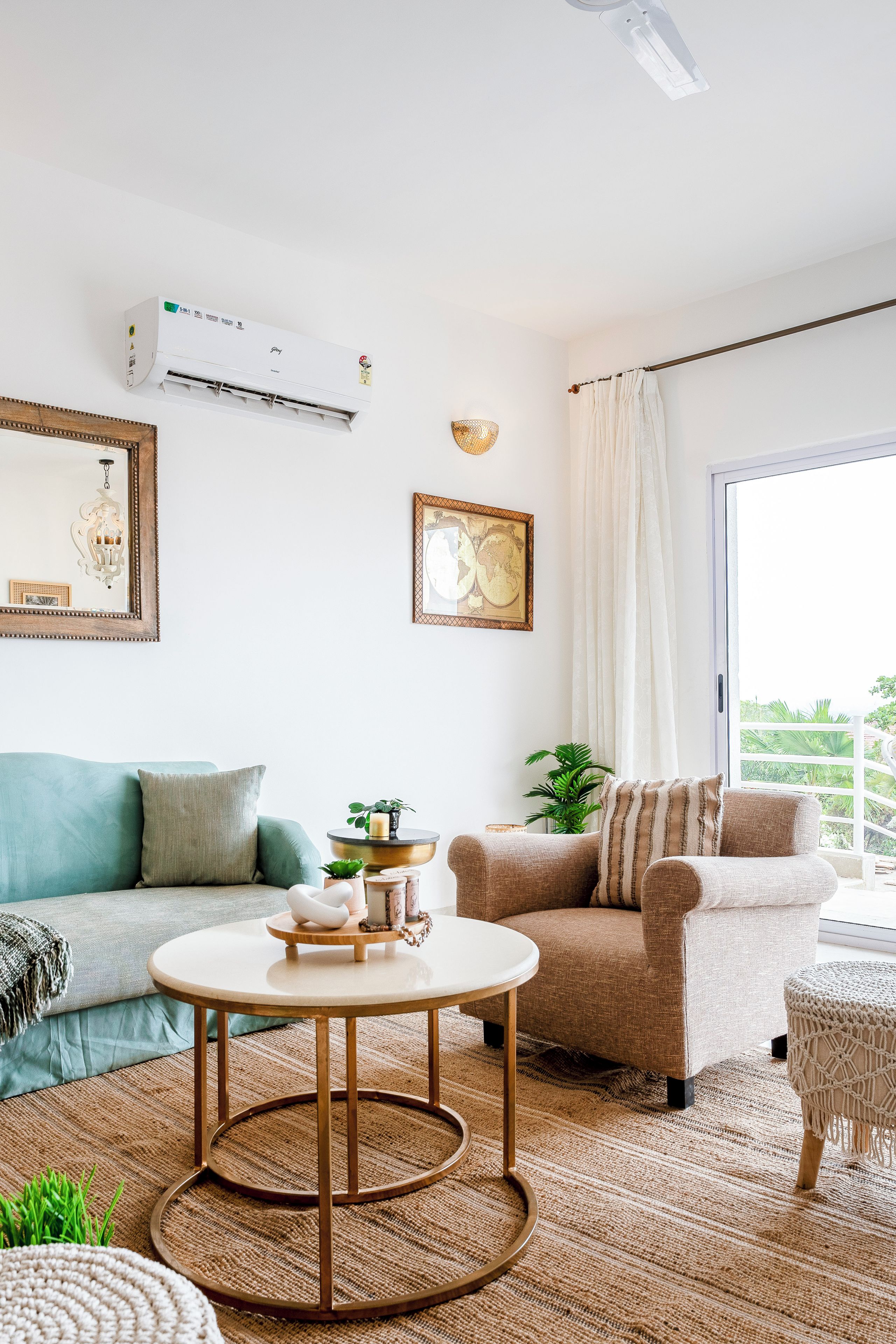 A living room with a sofa, armchair, round coffee table, and a large window with curtains.