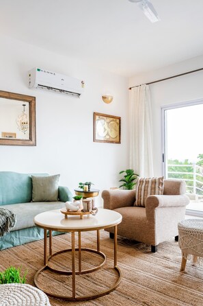 A living room with a sofa, armchair, round coffee table, and a large window with curtains. - Staymaster Casa Rysa-3BR-Pool & Sea View (Nerul)