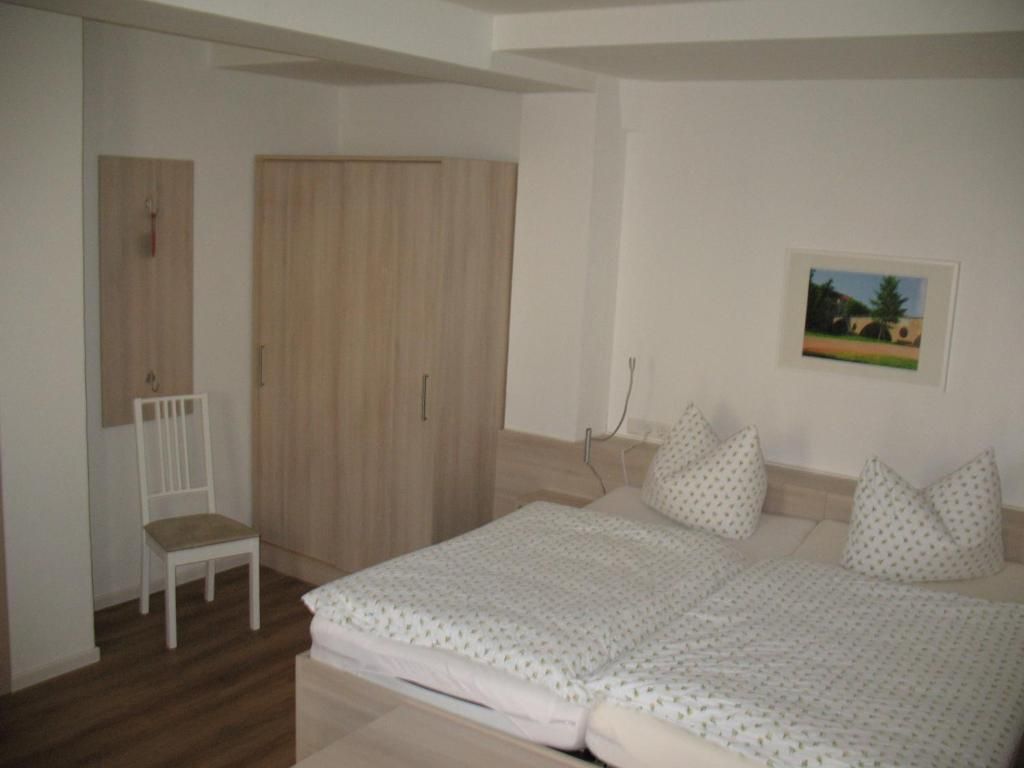 Une chambre à coucher avec un lit, une chaise, une armoire et un tableau au mur.