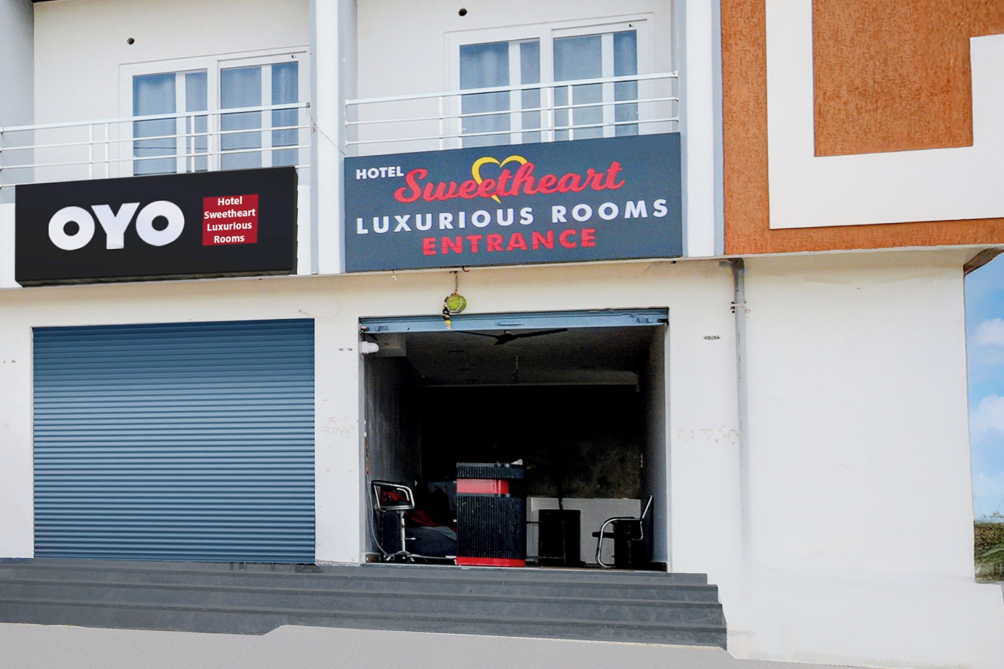 Ein Hotel Eingang mit einem Schild für 'Sweetheart Luxury Rooms' und einer geschlossenen, blauen Rolltür.