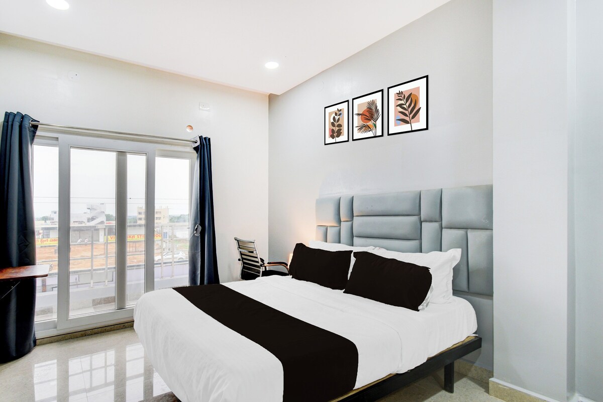 Habitación de hotel con cama, ventana con cortinas, vista al exterior y tres cuadros en la pared.