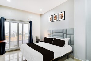 Habitación de hotel con cama, ventana con cortinas, vista al exterior y tres cuadros en la pared.