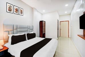 Una habitación de hotel con cama, mesita de noche, televisor y armario.