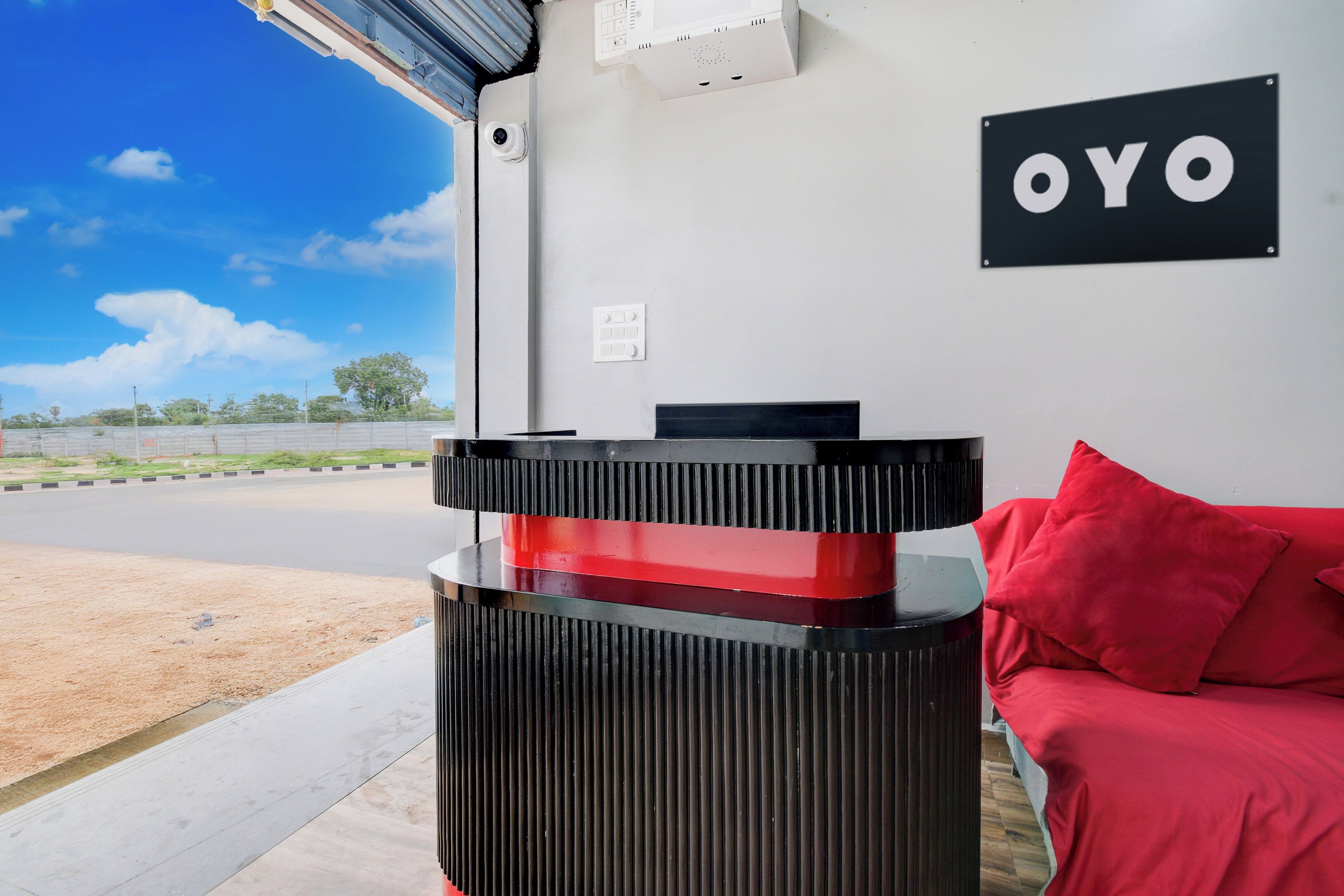 Ein Empfangsschalter mit schwarzem und rotem Design, ein rotes Sofa und ein 'OYO'-Schild an der Wand.