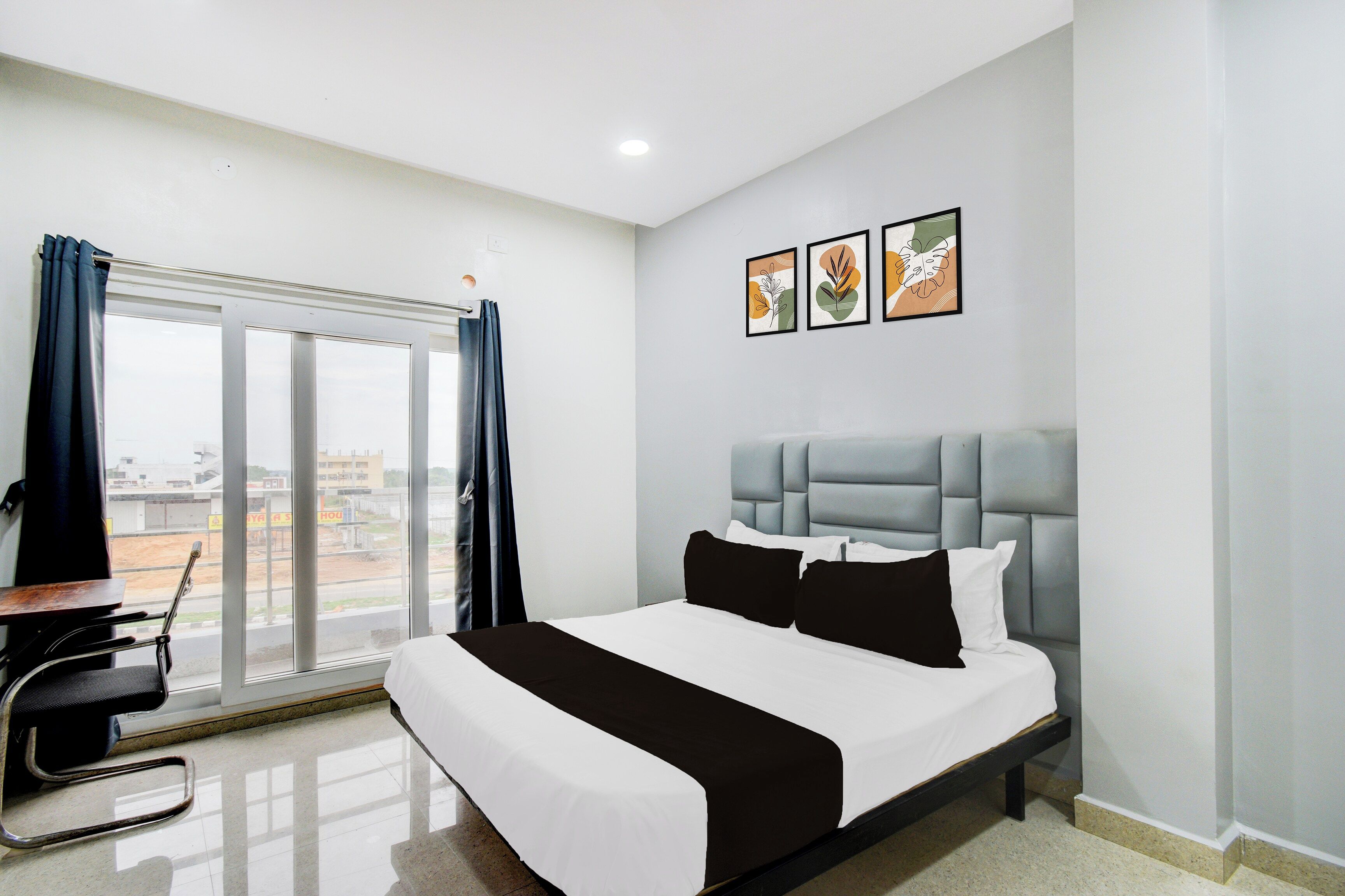 A hotel room with a bed, a desk, and a view of the outside.