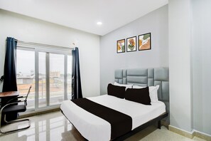 Una habitación de hotel con cama, escritorio y vista al exterior.