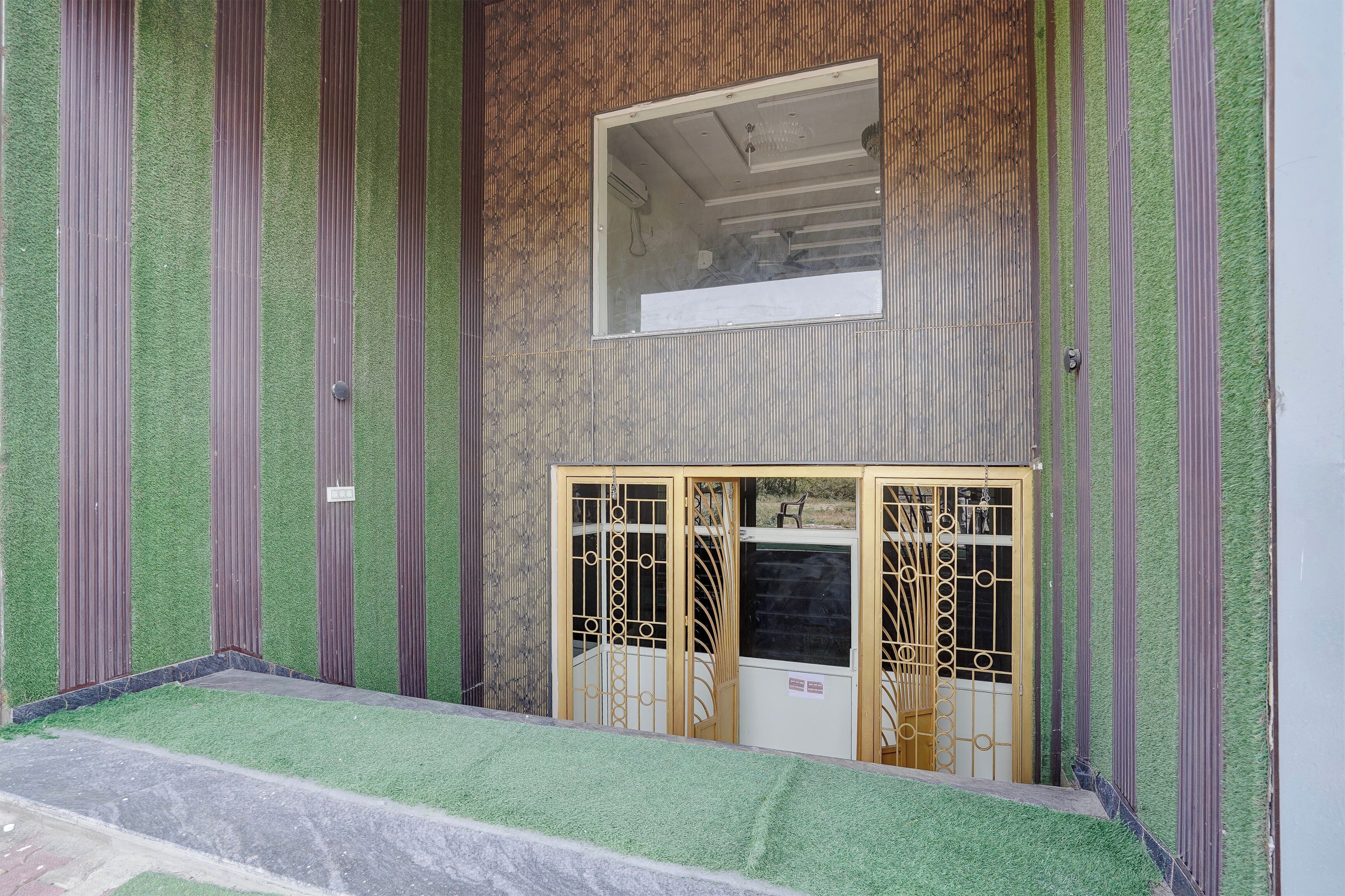 A building entrance with a metal gate, a small window above the door, and a staircase leading up to the entrance.