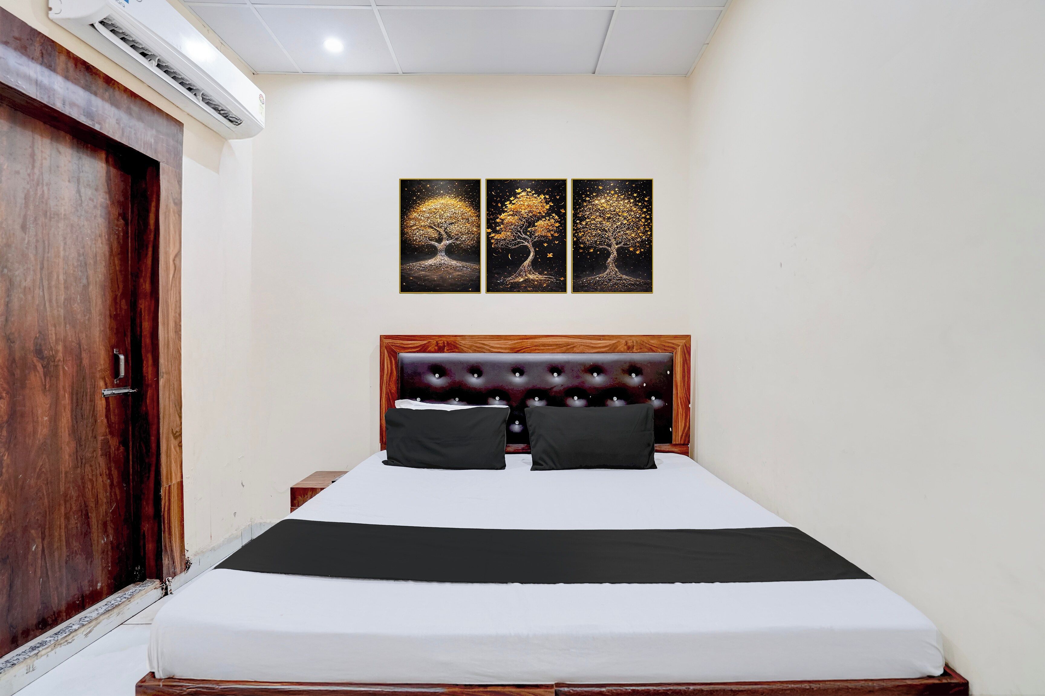 A bedroom with a bed, a wooden headboard, a nightstand, and a wall-mounted air conditioner.