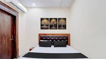 A bedroom with a bed, a wooden headboard, a nightstand, and a wall-mounted air conditioner.