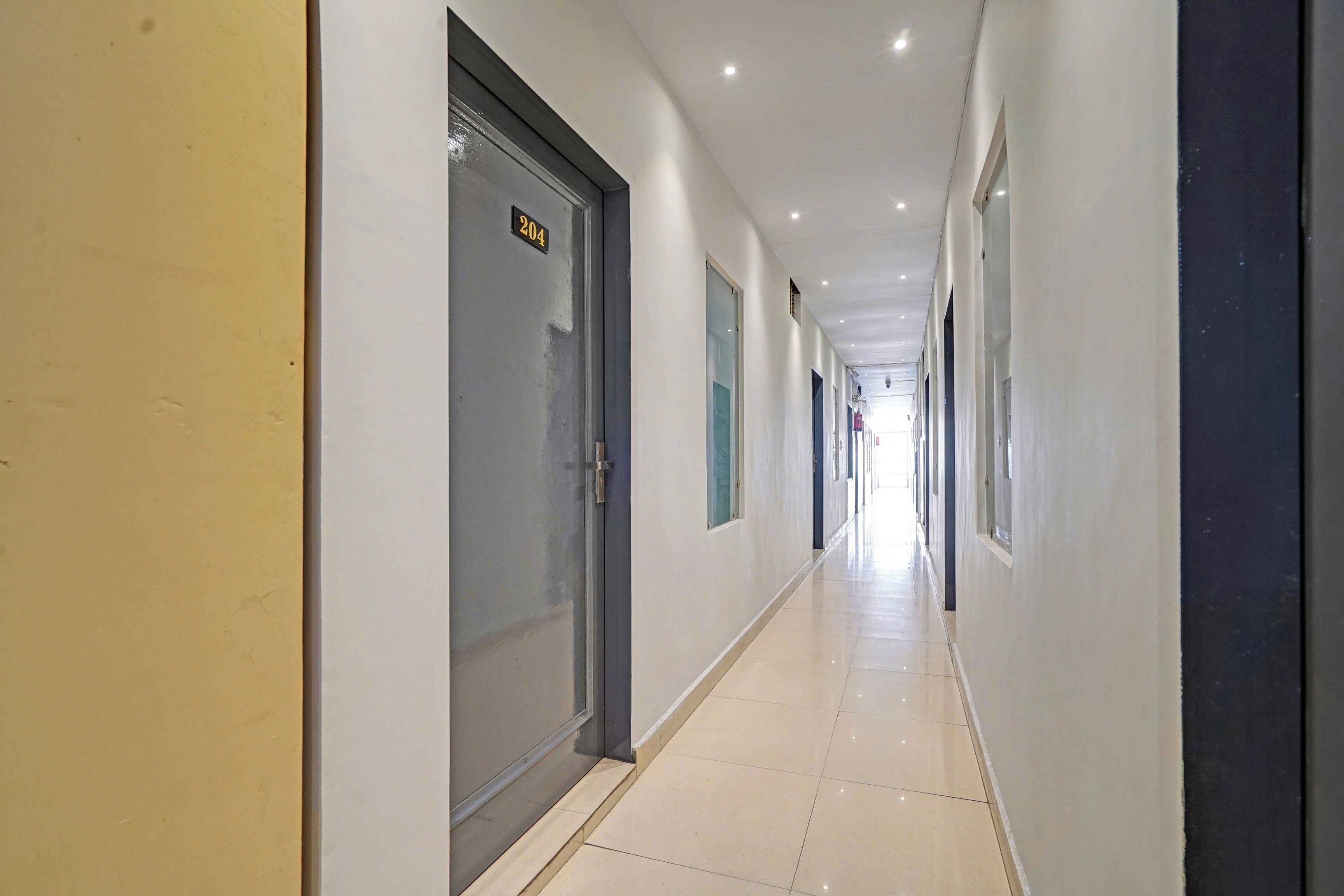 A corridor with doors, a tiled floor, and a ceiling with recessed lighting.