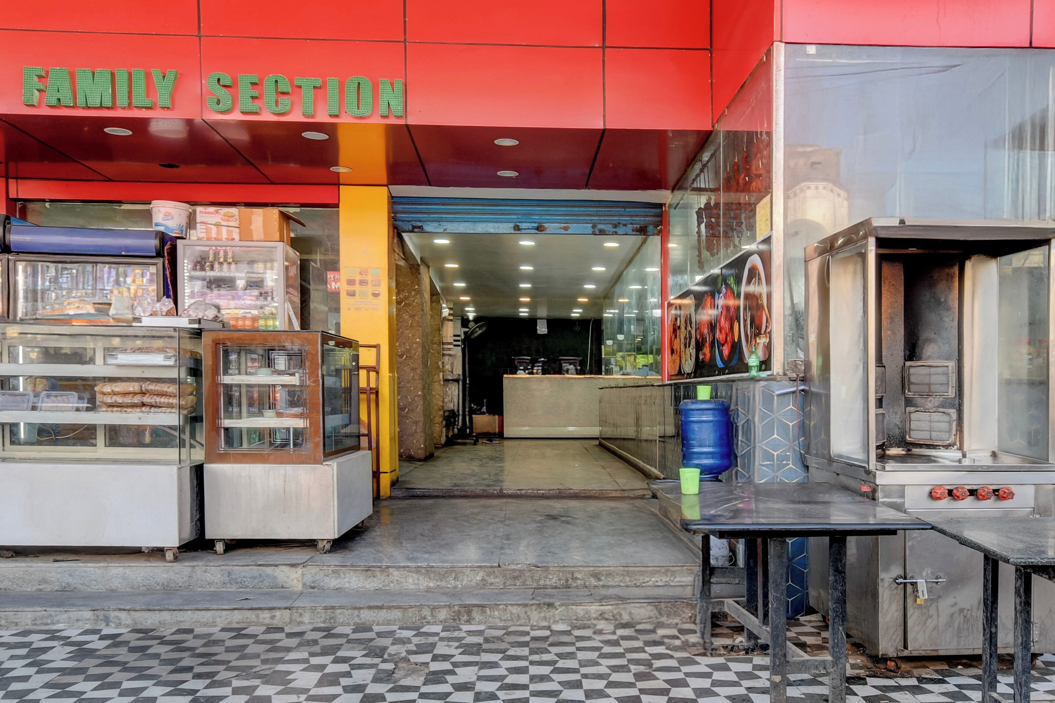 Un escaparate con un letrero que dice 'SECCIÓN FAMILIAR', máquinas expendedoras y un mostrador con un menú.