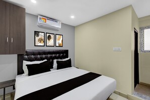 Un dormitorio con cama, cabecera, armario y obras de arte en la pared.