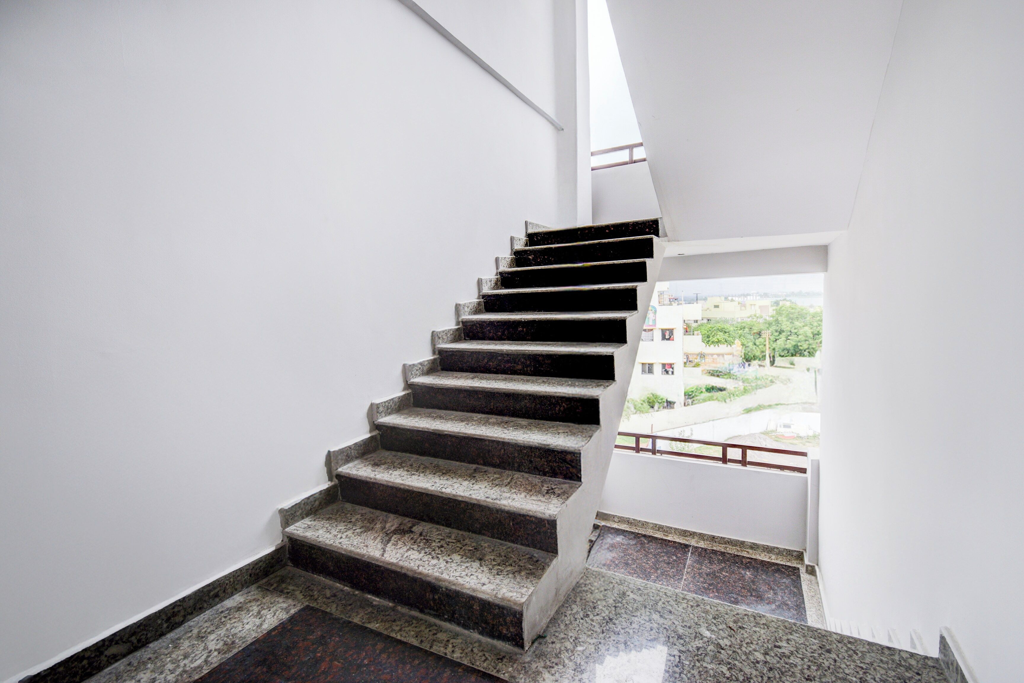 A staircase with a view of buildings and greenery outside.