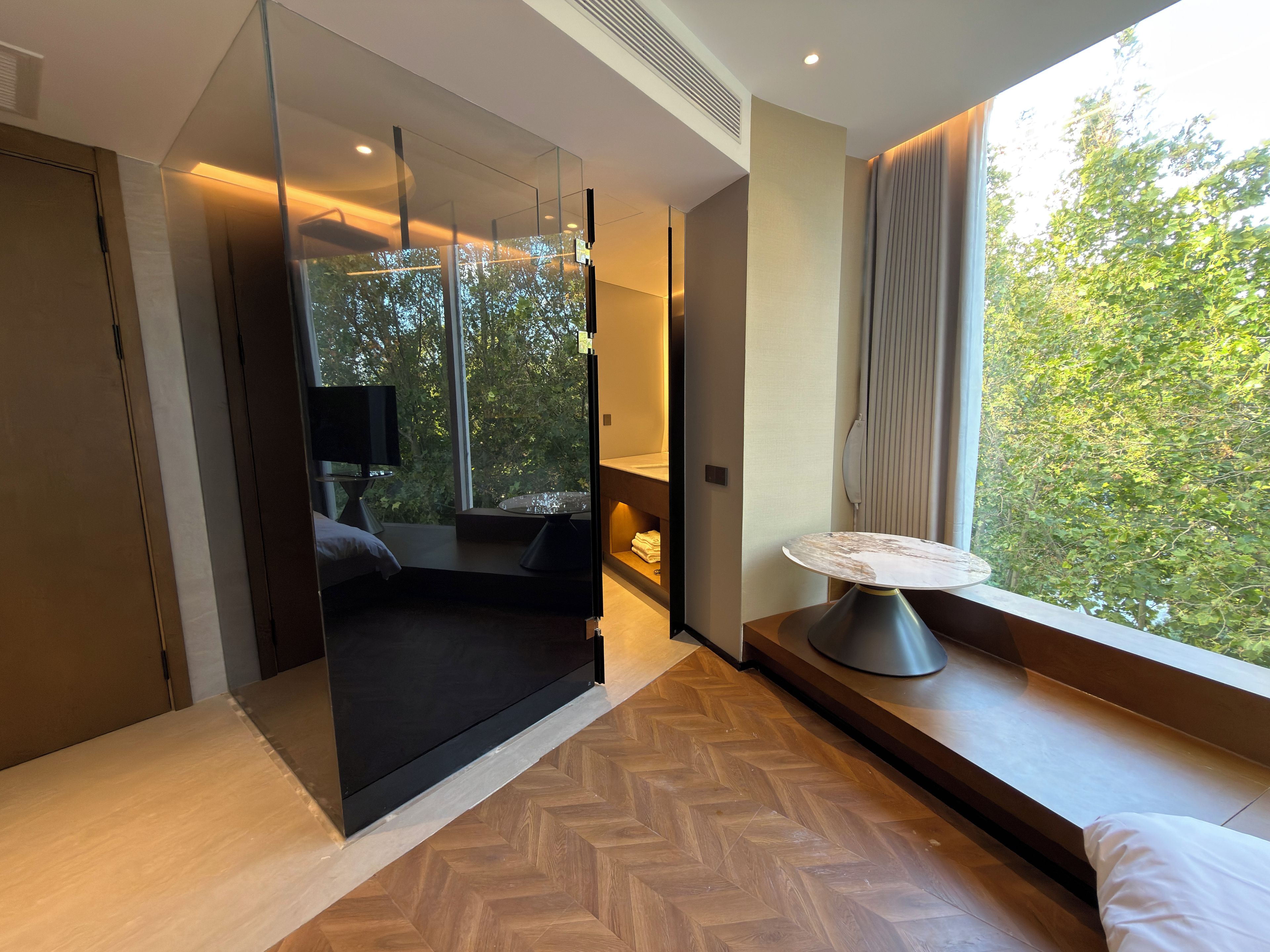 A modern room with a large window, a sofa, a table, and a TV.