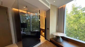 A modern room with a large window, a sofa, a table, and a TV.