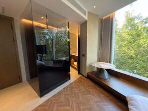 Una habitación moderna con un ventanal grande, un sofá, una mesa y un televisor.
