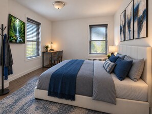 Un dormitorio con una cama, un escritorio y dos ventanas con persianas.