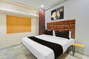Habitación de hotel con una cama grande, cabecera con diseño texturizado, mesita de noche pequeña y una obra de arte colgada en la pared.