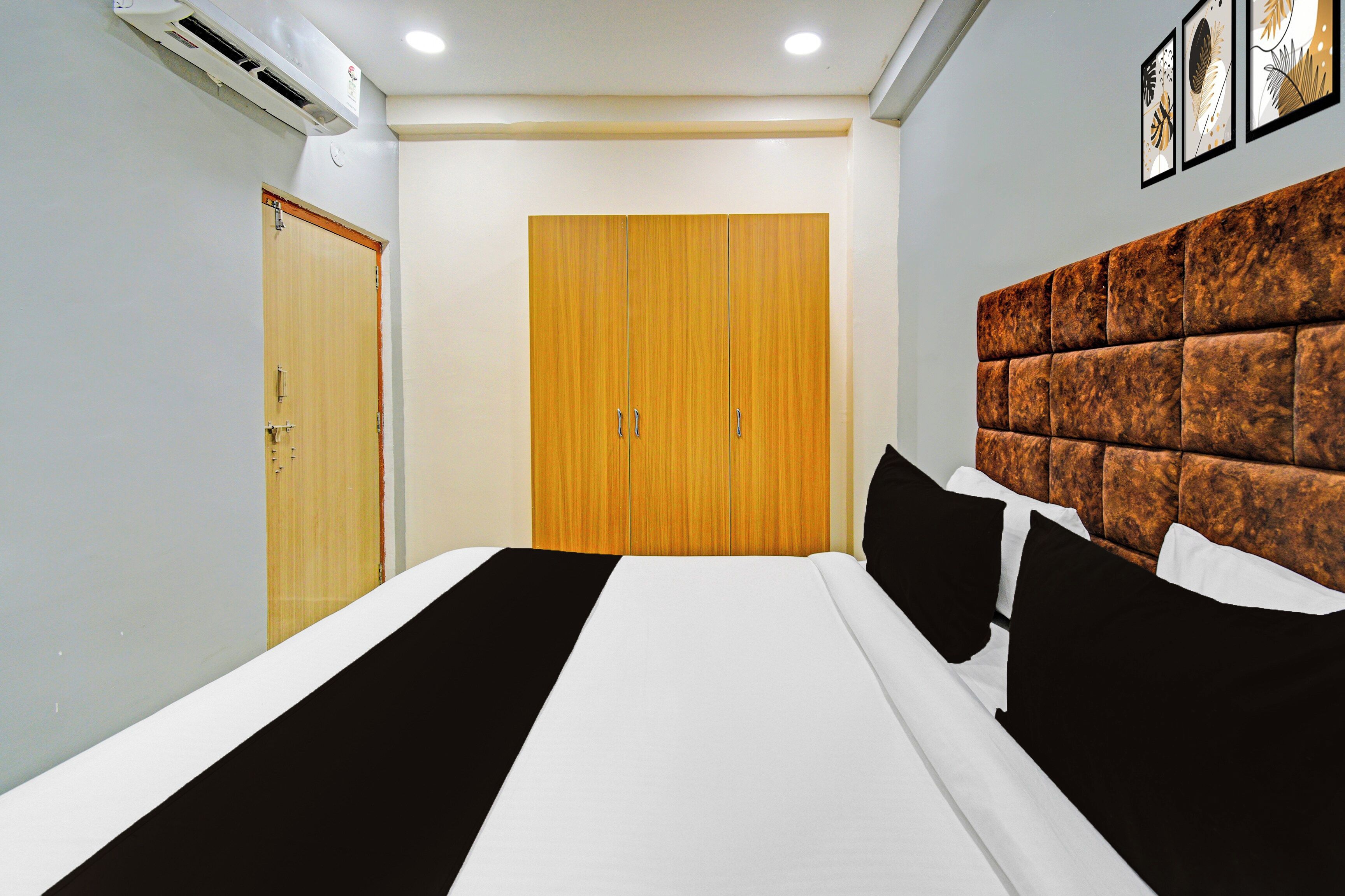 Ein Hotelzimmer mit einem großen Bett, einem Holzschrank und einer Wand-Klimaanlage.