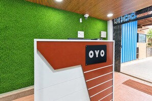 Una recepción con pared verde y un letrero que dice 'OYO'.