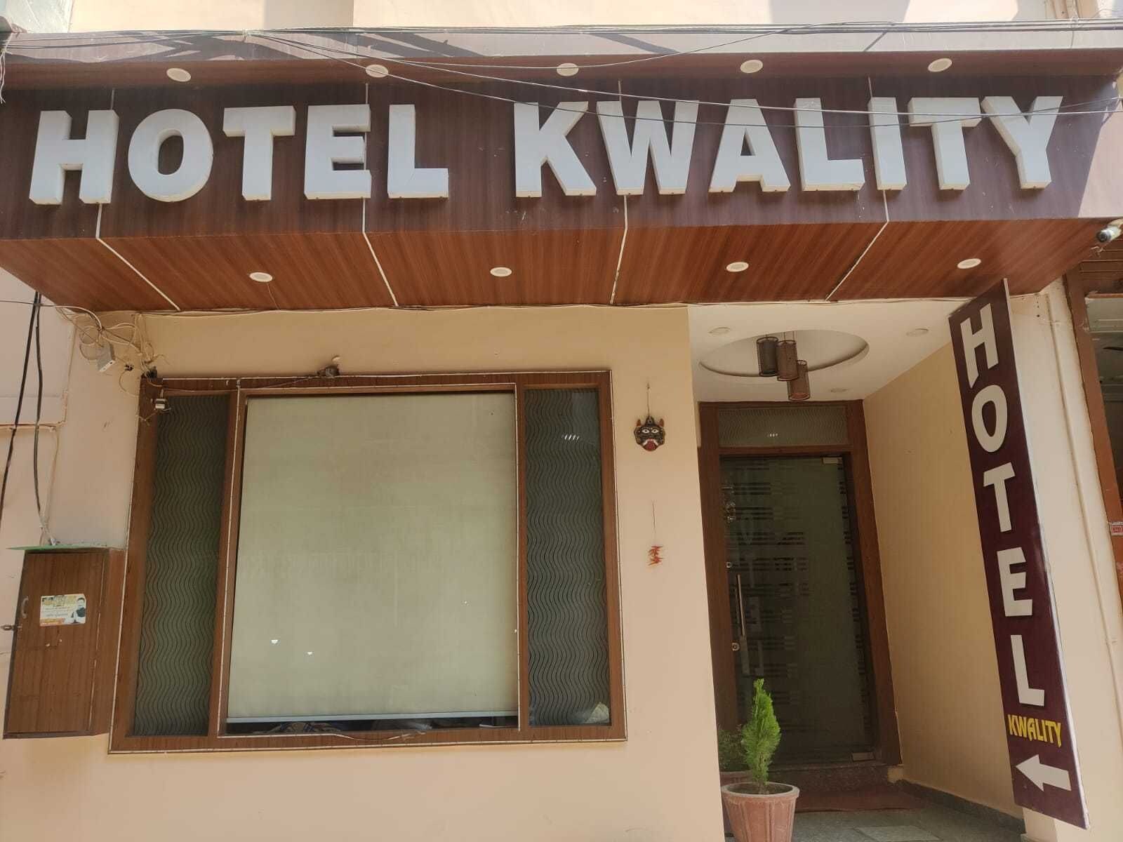 A hotel sign with the name 'HOTEL KWALITY' and a directional arrow pointing left.