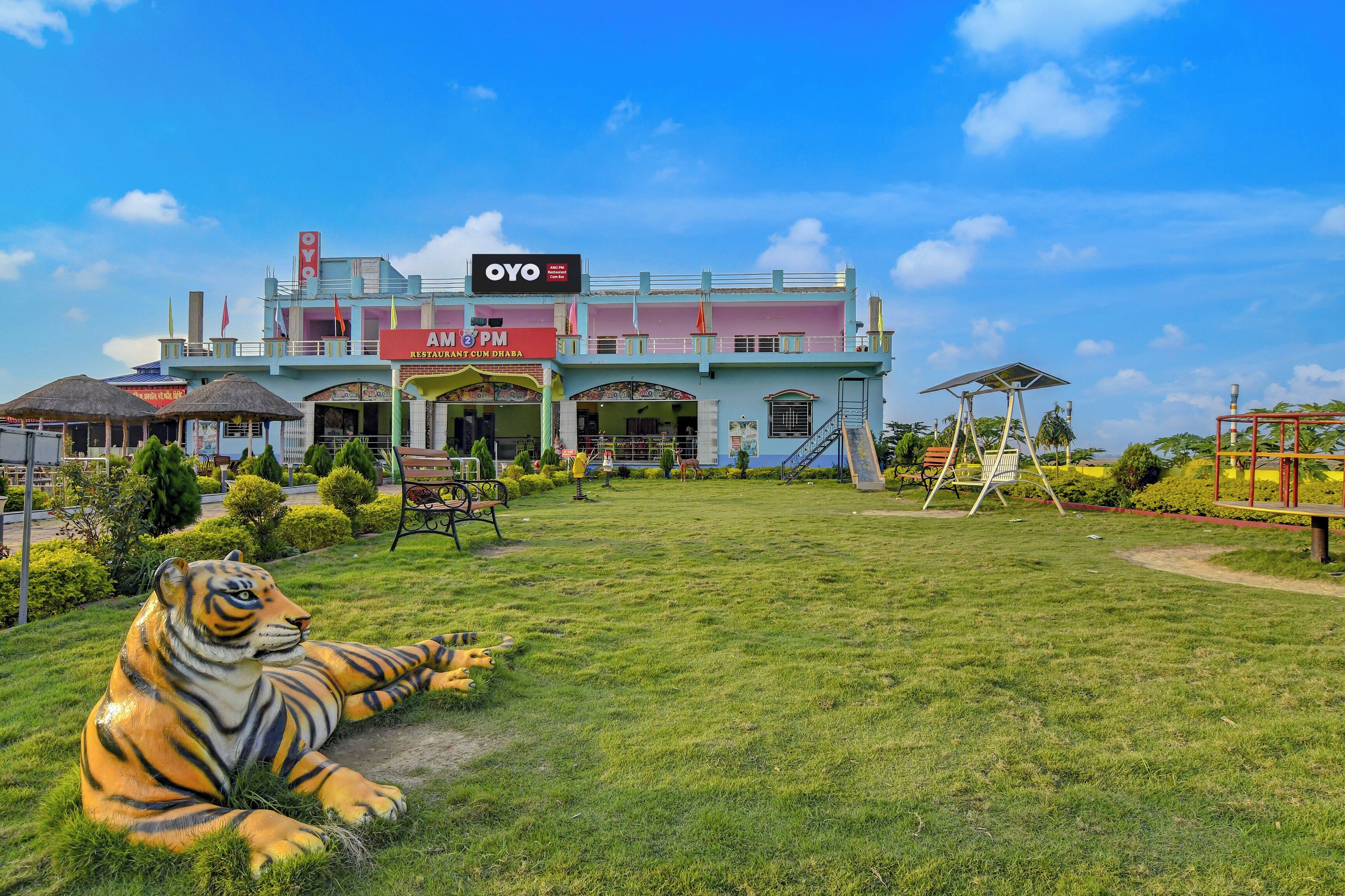 Un edificio con un restaurante llamado 'AM 2 PM' y una gran estatua de tigre al frente.