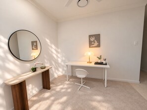 A modern, minimalist room with a round mirror, a desk with a chair, a small bench, and a wall-mounted lamp. - Stillwood House | Slow Days, Soft Nights, family home @ park ridge. (Park Ridge)