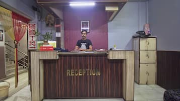 A hotel reception desk with a sign reading 'RECEPTION' and a 'NO CREDIT' sign above it.