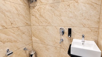 A bathroom with a white toilet, a sink, a shower, and a hand dryer.