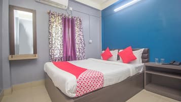Une chambre d’hôtel avec un lit, une table de chevet, un miroir et une fenêtre avec des rideaux.