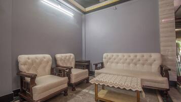 A room with a sofa, two armchairs, a small table, and a patterned tablecloth.