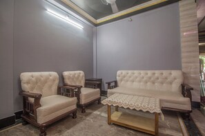 A room with a sofa, two armchairs, a small table, and a patterned tablecloth. - Hotel O Arya International (Siliguri)
