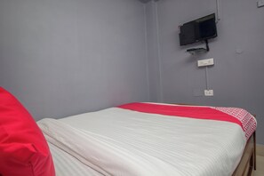 A single bed with a white and red bedspread, a television mounted on the wall, and a power outlet below it. - Hotel O Arya International (Siliguri)