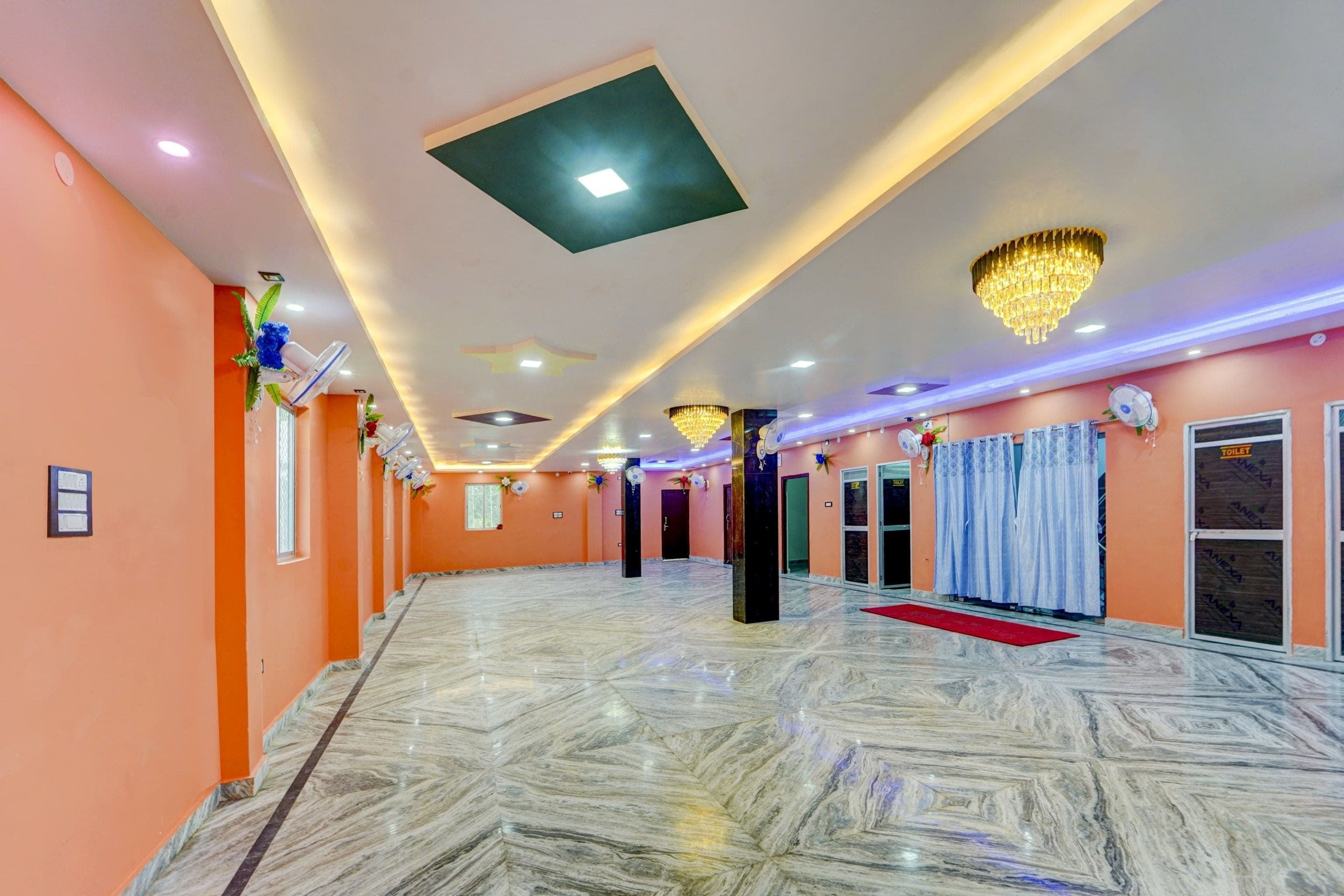 A spacious hotel lobby with marble flooring, ceiling lights, and a chandelier.
