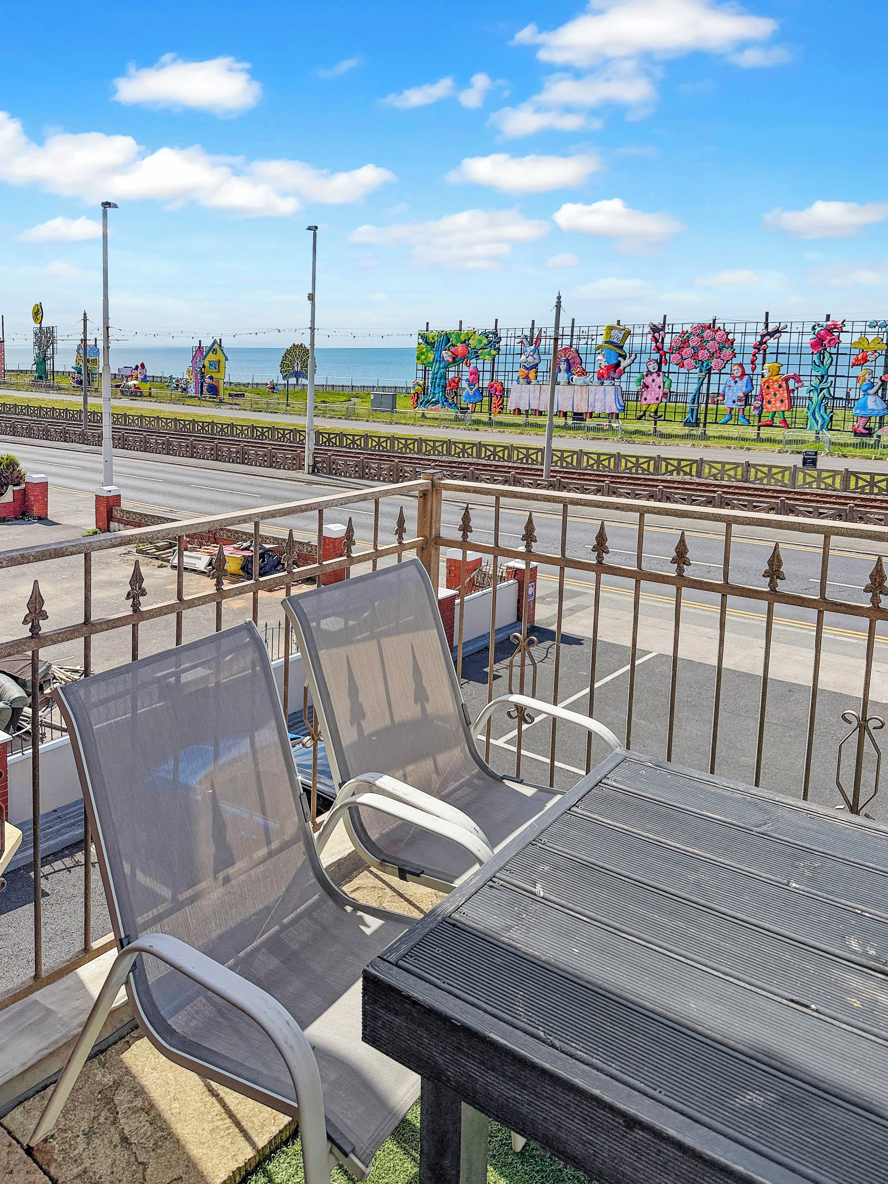 Terrasse extérieure offrant une vue sur une fresque murale colorée et l’océan.