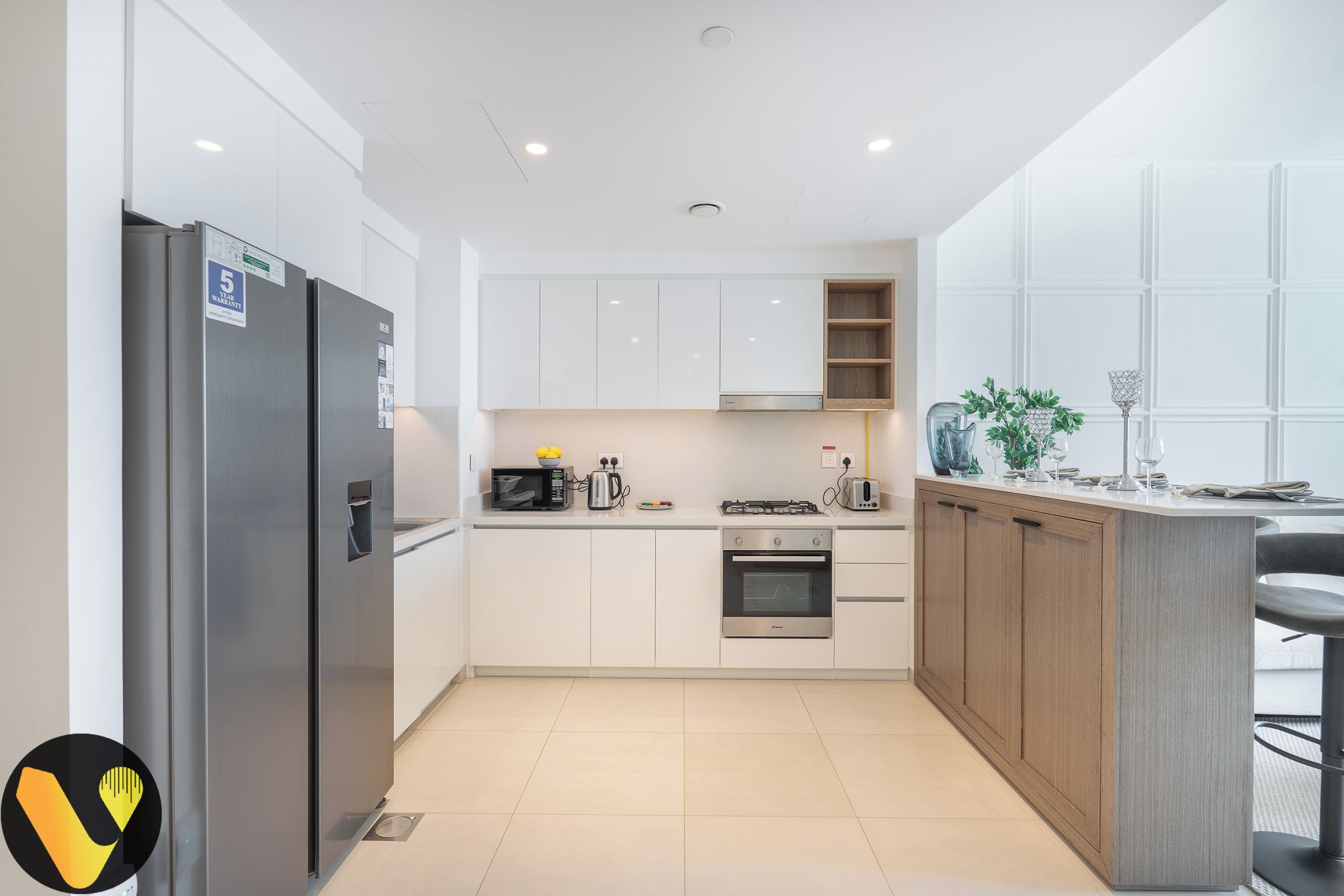 A modern kitchen with white cabinets, a stainless steel refrigerator, a built-in oven, and a microwave.