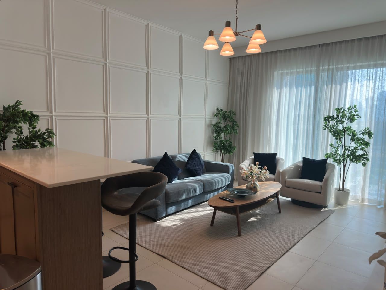 A modern living room with a sofa, armchairs, a coffee table, and a dining area.
