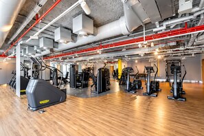 A gym with various exercise equipment, including treadmills and weight machines, and a polished wooden floor. - Vogue | Downtown with Easy Access to Dubai Mall (Dubai)