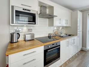 A modern kitchen with white cabinetry, a stainless steel toaster, a kettle, and a built-in oven. - Granada Apartments Burbage flat 3 1st floor rear (Blackpool FY2 9JS)
