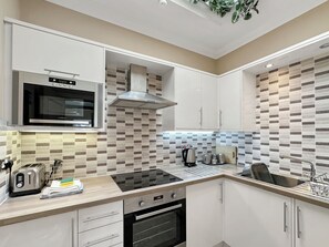 A modern kitchen with a built-in microwave, stove, oven, and a kettle on the countertop. - Granada Apartments Burbage flat 6 2nd floor front sea view (Blackpool FY2 9JS)