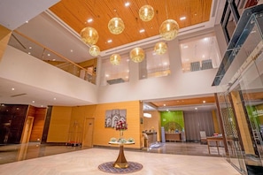 A spacious lobby with a high ceiling, multiple floors, and a reception desk. - Park Inn by Radisson Lucknow Vikas Nagar (Unnao)