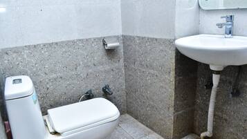 Une petite salle de bain équipée de toilettes, d’un lavabo et d’un distributeur de serviettes en papier.