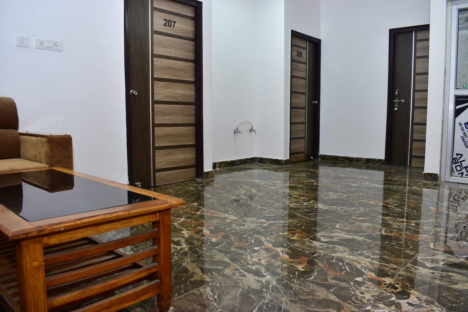 Un vestíbulo de hotel con piso de mármol, una mesa de madera y dos puertas con los números 207 y 208.