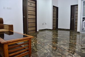 Un vestíbulo de hotel con piso de mármol, una mesa de madera y dos puertas con los números 207 y 208.