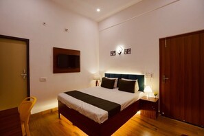 A hotel room with a bed, bedside tables, a television, and a wooden door. - Hotel O 7 Orchid (Sultanpur)