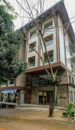 Um edifício com várias andares, fachada de pedra, uma varanda e uma loja com letreiros.