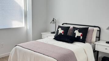 A bedroom with a bed, bedside tables, a lamp, a window, and a rug.