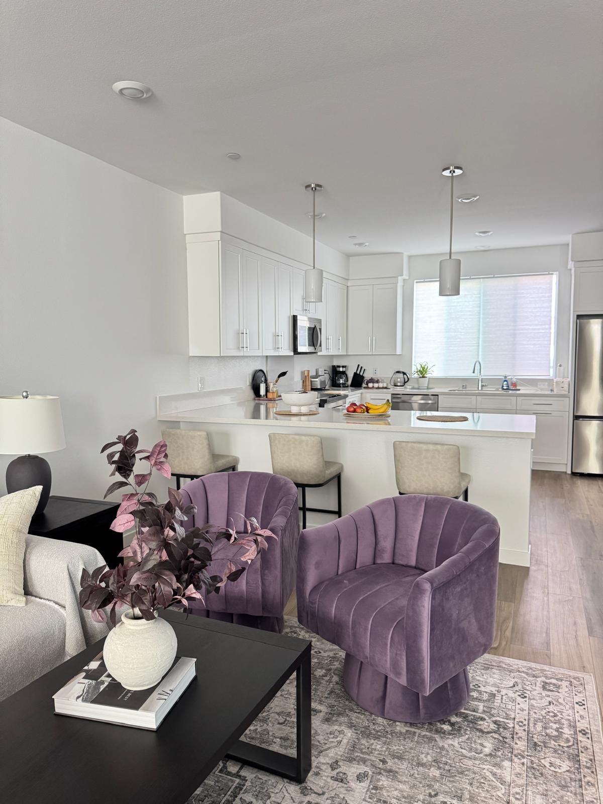 A modern kitchen with white cabinets, a central island, and a stainless steel refrigerator.