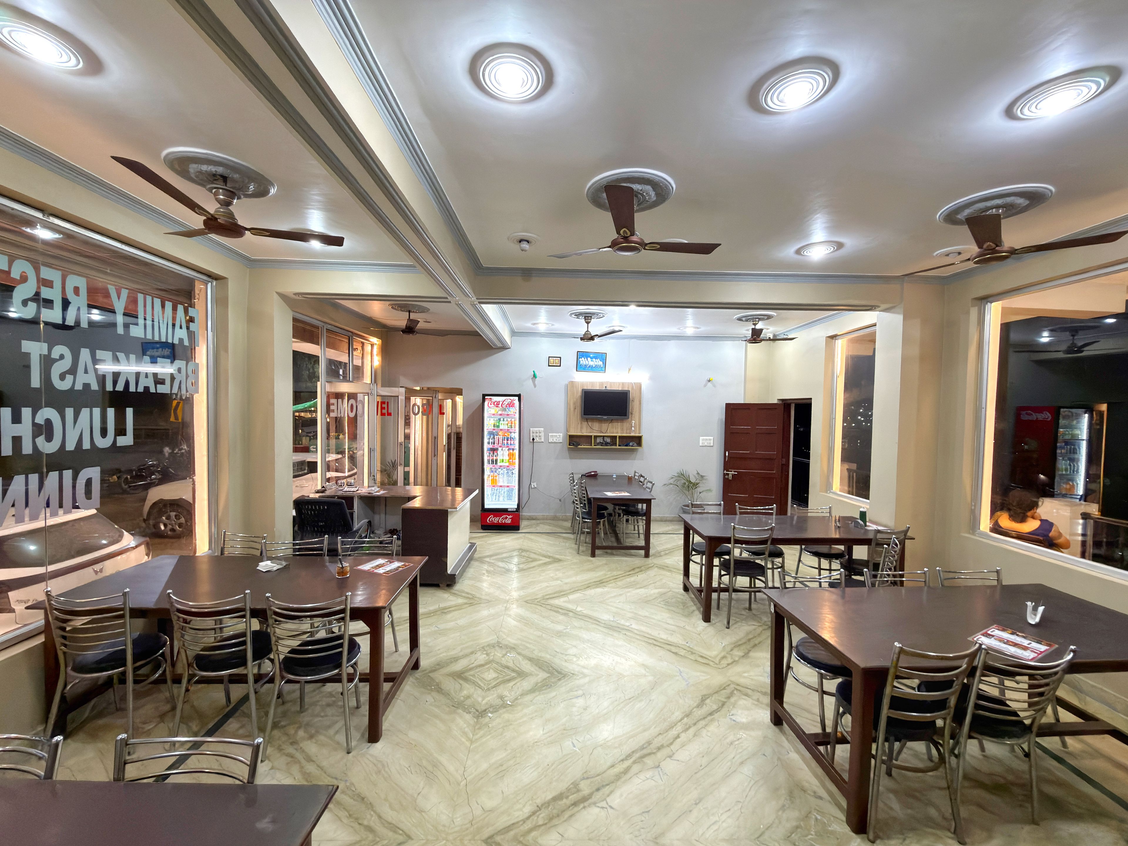 Ein Restaurant mit mehreren Tischen, Stühlen, Deckenventilatoren und einem Verkaufsautomaten.